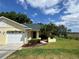 Beautiful home with a lush green lawn, tropical landscaping, and a two-car garage at 8829 Courtyard Ln, Groveland, FL 34736