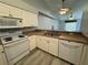 Well-equipped kitchen with white appliances and cabinetry and a view to the adjacent living space at 8829 Courtyard Ln, Groveland, FL 34736