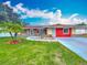 Welcoming home with manicured front lawn, stone accents and a vibrant red exterior, all under a blue sky at 898 Hendry Dr, Orlando, FL 32822