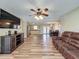 Open living room with hardwood floors, a ceiling fan, entertainment center, and view of kitchen at 898 Hendry Dr, Orlando, FL 32822