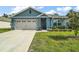 Charming blue one-story home featuring a two-car garage and well-manicured lawn on a sunny day at 6768 Coral Berry Dr, Mount Dora, FL 32757