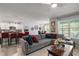 Open concept living room featuring a plush gray sofa, large windows and easy access to kitchen at 6768 Coral Berry Dr, Mount Dora, FL 32757