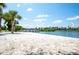 Picturesque white sand beach by a calm lake surrounded by palm trees, lush greenery and well-manicured lawn at 1000 Park Club Dr, Kissimmee, FL 34746