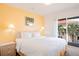 Bright bedroom with queen-sized bed, nightstand, and balcony offering views of palm trees at 1000 Park Club Dr, Kissimmee, FL 34746