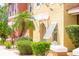 Townhome exterior featuring colorful stucco, lush landscaping, and shuttered windows with pergola at 1000 Park Club Dr, Kissimmee, FL 34746