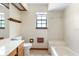 Well-lit bathroom featuring white tile, a built-in tub, and a window for natural light at 1003 Chesterfield Cir, Winter Springs, FL 32708
