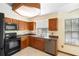 Traditional kitchen with wood cabinets, black appliances and a view from the window at 1003 Chesterfield Cir, Winter Springs, FL 32708