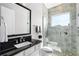 Modern bathroom features a black granite countertop, gray tiled walk-in shower, and neutral color palette at 10196 Bucklow Hill Dr, Orlando, FL 32832
