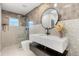 Stylish bathroom with a modern floating vanity, decorative round mirror and glass enclosed shower at 1113 Black Acre Trl, Winter Springs, FL 32708