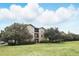 Well-manicured grounds and a multi-story apartment building with large trees enhancing the curb appeal at 114 Vista Verdi Cir # 136, Lake Mary, FL 32746