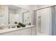 Bright bathroom featuring a double vanity, neutral countertops, and tiled shower at 1196 Alstonia Ln, Mount Dora, FL 32757