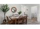 Comfortable dining area featuring a wooden table set for six, complemented by a stylish mirror and hardwood flooring at 1200 Alstonia Ln, Mount Dora, FL 32757