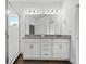 Bathroom featuring double sinks with granite counter, white cabinets and hardware, large mirror, and walk-in glass shower at 14259 Kellogg Ave, Orlando, FL 32827