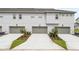Exterior view of three attached homes with concrete driveways and gray garage doors and light gray exterior paint at 14259 Kellogg Ave, Orlando, FL 32827