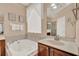 Bright bathroom with garden tub, tile surround, and a vanity with solid surface countertop at 1585 Maidencane Loop, Oviedo, FL 32765