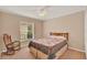 Cozy bedroom with a bed, rocking chair, window, and neutral-colored walls and carpet at 1585 Maidencane Loop, Oviedo, FL 32765