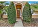 Inviting front entry featuring a solid wood door, decorative wreath, and manicured shrubs at 1585 Maidencane Loop, Oviedo, FL 32765