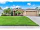 Charming tan home featuring a lush green lawn, manicured landscaping, and a two-car garage in a quiet neighborhood at 1585 Maidencane Loop, Oviedo, FL 32765