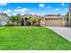 Charming single-story tan home featuring a lush green lawn, manicured landscaping, and a two-car garage at 1585 Maidencane Loop, Oviedo, FL 32765