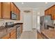 Well-equipped kitchen featuring wood cabinetry, tile flooring, and modern stainless steel appliances at 1585 Maidencane Loop, Oviedo, FL 32765