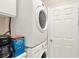 A bright laundry room with a stacked washer and dryer unit and white cabinetry at 1585 Maidencane Loop, Oviedo, FL 32765