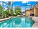 A lagoon-style pool and spa surrounded by a screened enclosure and lush landscaping at 1585 Maidencane Loop, Oviedo, FL 32765