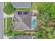Top-down aerial view shows the roof, solar panels, screened-in pool, hot tub, and surroundings at 1610 River Birch Ave, Oviedo, FL 32765