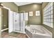 Bathroom features a soaking tub, glass enclosed shower, and decorative window for natural light at 1610 River Birch Ave, Oviedo, FL 32765