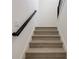Elegant staircase featuring wood steps, a black handrail, and white walls at 18964 Rawson St, Orlando, FL 32827