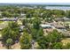 Aerial view of a neighborhood with mature trees, a glimpse of a lake in the distance, and blue skies at 2014 10Th Nw St, Winter Haven, FL 33881