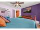 Cozy bedroom featuring vibrant color walls, ceiling fan, TV, and comfortable bed with decorative pillows at 2665 E Juliet Dr, Deltona, FL 32738