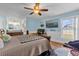 Light blue bedroom featuring a ceiling fan, TV, wooden floors, a comfortable bed and a workspace at 2665 E Juliet Dr, Deltona, FL 32738