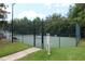 A community tennis court with green surface and secure fencing, surrounded by trees at 280 Celebration Blvd # 208, Kissimmee, FL 34747