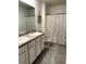 Well-lit bathroom with double vanity sinks, decorative mirror, and modern shower curtain at 321 Jovana Rd, Davenport, FL 33837