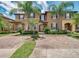 Charming two-story townhome featuring a brick driveway and well-manicured landscaping, including mature palm trees at 416 Calabria Ave, Davenport, FL 33897