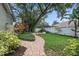 Professionally landscaped backyard with a winding brick path, lush lawn, and mature trees at 4411 Little Water St, Orlando, FL 32817