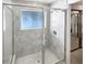Updated glass shower in bathroom features tiled walls, small window, and silver fixtures at 4993 Heatherstone Pl, Orlando, FL 32812