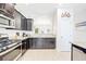 Well-lit kitchen with modern appliances, dark cabinets, and view of the dining area at 5156 Oakbourne Ave, Davenport, FL 33837