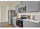 Well-equipped kitchen with sleek gray cabinets, stainless steel appliances, and white countertops at 5290 Scrub Mint Ln, Apopka, FL 32712