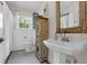 Bright bathroom featuring a pedestal sink, unique cabinet, and vintage-style mirror at 604 Cherokee Dr, Orlando, FL 32801