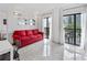 Bright living room with a red couch, balcony access, and stylish wall mirrors at 6165 Carrier Dr # 1304, Orlando, FL 32819