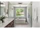 Modern bathroom featuring a soaking tub with a window view and a walk-in shower with elegant fixtures at 705 N Lake Sybelia Dr, Maitland, FL 32751