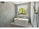 Bright soaking tub with nature view and modern shower fixtures within a beautifully tiled bathroom at 705 N Lake Sybelia Dr, Maitland, FL 32751