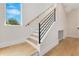 Modern staircase with wooden treads, a black metal railing, and natural light from a nearby window at 705 N Lake Sybelia Dr, Maitland, FL 32751