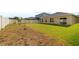A spacious backyard with healthy green grass, with a white fence and view of the neighboring home at 714 Golden Elm Dr, Apopka, FL 32703