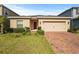 Charming single-story home featuring a two-car garage and brick paved driveway at 714 Golden Elm Dr, Apopka, FL 32703