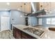 Kitchen island featuring granite countertops, wood cabinets, and a stainless steel range hood at 723 River Run Rd, Osteen, FL 32764