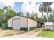 Spacious outbuilding with large roll up door, green trim and ample space for a workshop or storage at 723 River Run Rd, Osteen, FL 32764