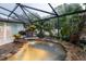 Screened-in hot tub area featuring lush landscaping and rock waterfall feature at 789 Barger Dr, Deltona, FL 32738