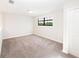 Bright bedroom featuring neutral carpet, light walls, a black trimmed window, and a white door at 7931 Rock Dove Dr, Winter Garden, FL 34787